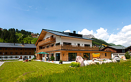 Hausansicht vom "Das Tannberg" im Sommer unter klarem Himmel.