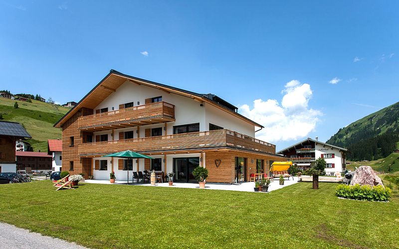Das Tannberg im Sommer mit Holzbalkonen, Terrasse und Garten